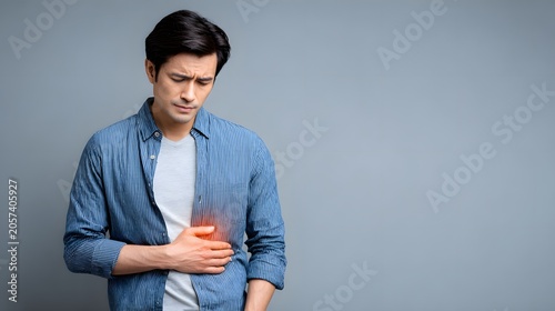 Asian man holding liver area with painful expression, glowing red liver graphic, healthcare photography