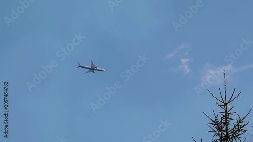 A passenger airliner flies by in the blue sky. The survey is conducted from the ground