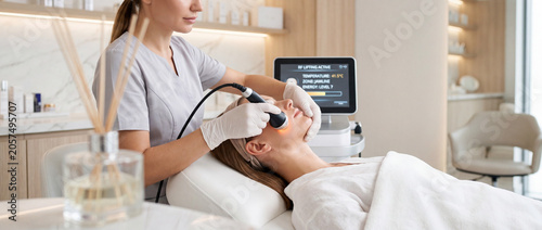 Professional facial RF treatment at modern medical spa with aesthetician performing skin tightening