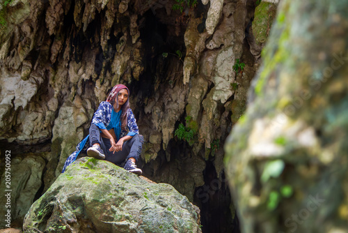 Young Woman Sitting on Rock in Cave Wearing Traditional Fashion