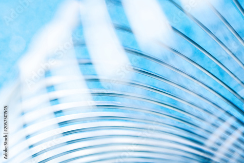 Close-up of shiny metal coils forming a dynamic pattern against bright blue. High-resolution tech background ideal for modern corporate and industrial layout designs. Photo
