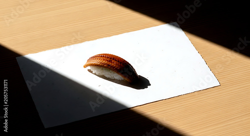 japanese minimalist. a piece of unagi nigiri on a blank sheet of handmade washi paper, creating a composition of form and shadow