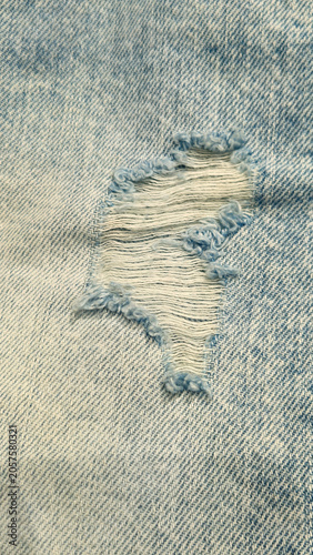 Close-up of a torn hole in jeans fabric