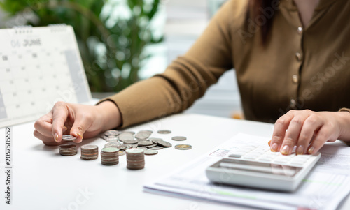 Canvastavla Young woman reviewing financial documents, calculating expenses, and organizing coin stacks for household budgeting, savings planning, money management, and financial control