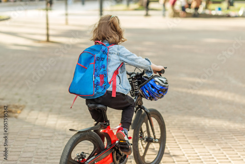 Child riding bicycle to school with backpack