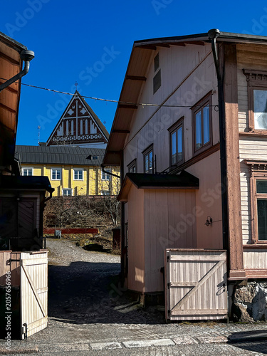 Traditional Old Wooden Finnish Houses on Medieval Street and Gable of Lutheran Cathedral in the Background in Porvoo (Borgå) Finland. 