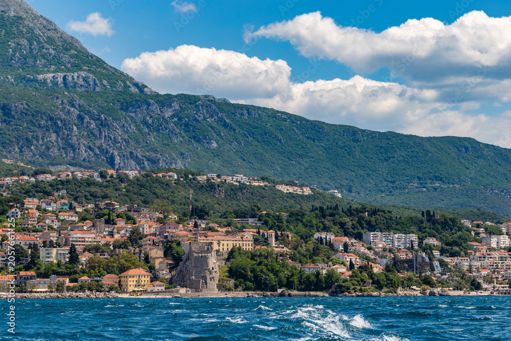 Fototapeta premium Imposing medieval stone fortress rising majestically above the sunlit harbor and marina of Herceg Novi