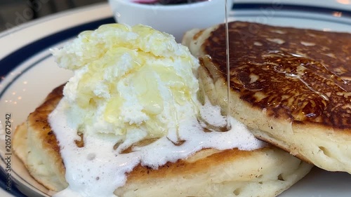 朝ご飯で食べるパンケーキ。ホイップクリームをトッピングしたパンケーキにメープルシロップをかける動画。