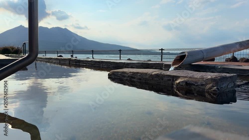 鹿児島県の桜島が望める足湯。足だけを入れる温泉。午後の桜島の風景が反射する水面の動画。