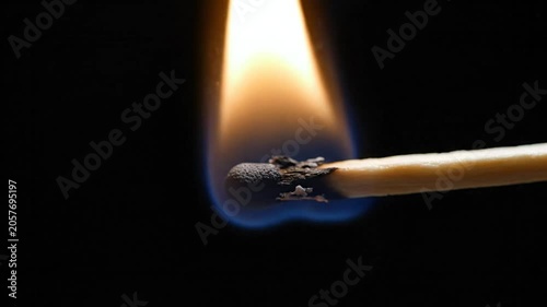 Burning matchstick with intense flame against black background, producing smoke and embers creating a captivating display