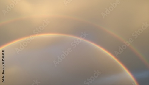 Konstfotografi A vibrant rainbow stretches across a serene sky with soft clouds and warm sunlig