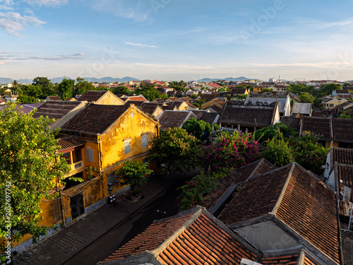 Historic yellow houses and flowering trees brighten a quiet street in Hoi An.