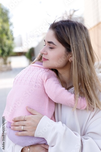 Mother hugs her little daughter during family walk and outdoor recreation.