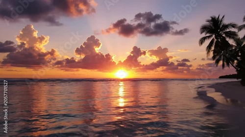 Tranquil tropical beach sunset with vibrant orange and pink colors reflecting on the calm ocean water