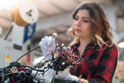 Fotografía Woman assembles robotic arm with wires and circuits in an industrial manufacturi