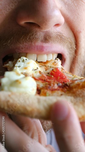 Extreme close up hungry bearded man eating slice italian pizza with mozzarella, tomatoes, savoring every bite of fast food meal with great appetite, pleasure. Bearded man eating delicious slice pizza