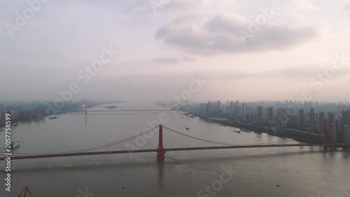 Aerial view of red suspension bridge and Wuhan skyline over the Yangtze River at dusk in Wuhan, China
