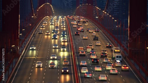 Evening Traffic on Illuminated Red Suspension Bridge in City