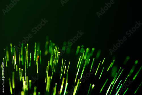 Radiant green fiber optic tips glow intensely, cutting through solid dark backdrop.