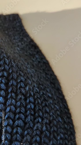 Detailed view of dark blue, textured crocheted fabric on soft beige background. Textile handmade close-up