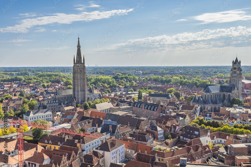 Obraz premium Bruges town in Belgium, Europe. Panoramic Aerial View of a Historic European Cityscape with Ancient Towers and Red Rooftops Under a Bright Blue Sky