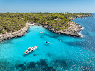 Leinwandbilder Türkis Aerial view of Cala Mondrago bay in Mallorca, Spain. Luxury yachts, boat anchored in turquoise sea water cove, rocky coast with green pine trees, sand beach on sunny day. Mediterranean drone landscape  © den-belitsky