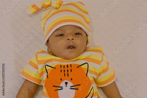 Baby in colorful outfit with cat design lying on the bed