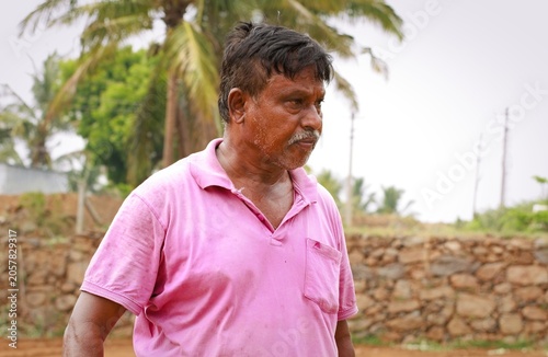 Man in pink shirt walking in rural area under cloudy sky