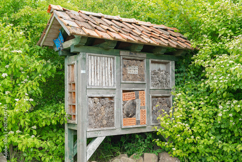 Large wooden insect hotel in green garden Wooden bug house shelter for biodiversity