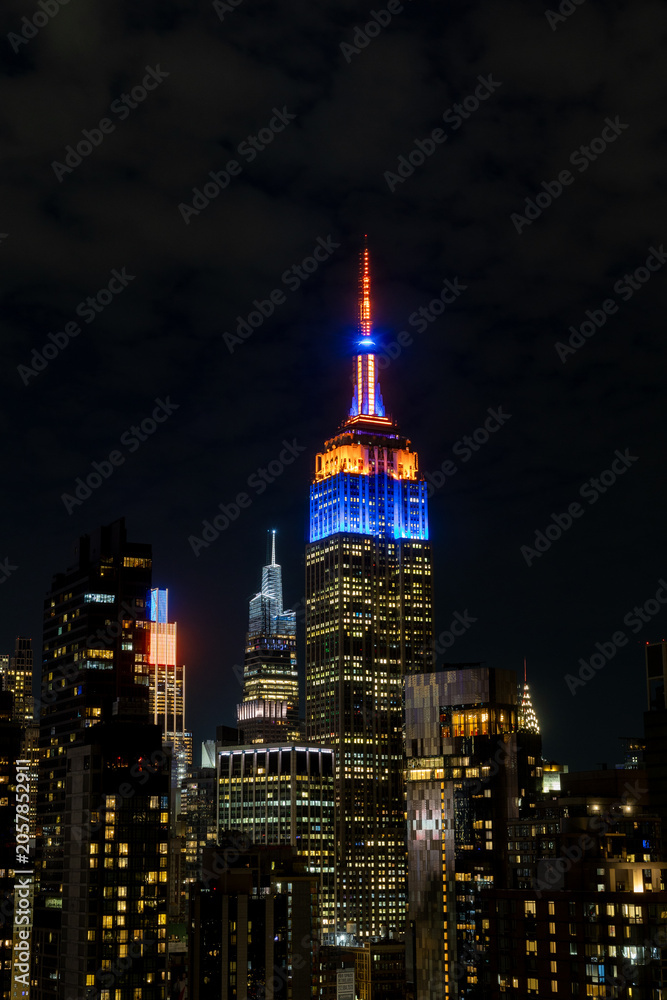 Naklejka premium New York, NY- May 21 2026: Manhattan skyline with the Empire State Building in New York Knicks colors
