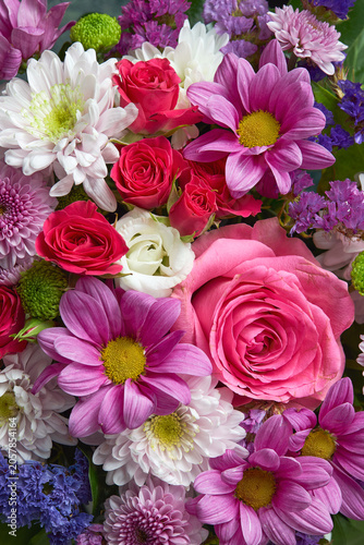 Close up view of a vibrant floral arrangement featuring pink roses, dahlias, chrysanthemums and white flowers.