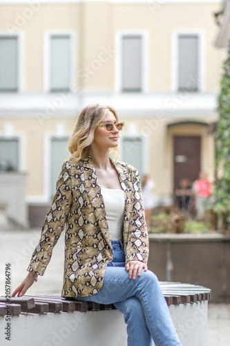 Portrait of a beautiful young blonde in the city center. The poses for photographs.