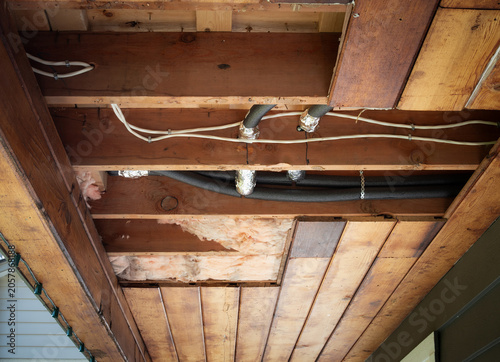 Fotografía Exposed insulation and wrapped plumbing pipes in open ceiling cavity