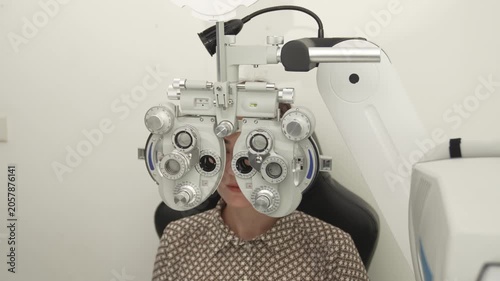 A positive female patient undergoes a professional vision check and refraction test using advanced ophthalmic equipment. This high-value commercial stock imagery represents preventative healthcare, pr