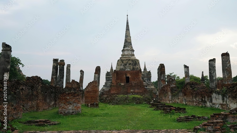 Obraz premium Ancient temple with tall spire and ruins in a grassy area