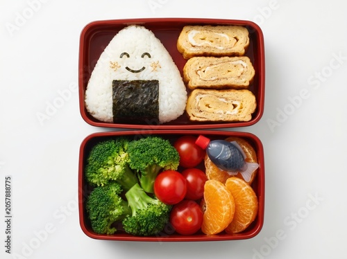 Cute bento box with onigiri and fresh vegetables
