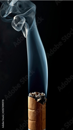Smoldering Cigarette Butt with Rising Smoke on Black Background