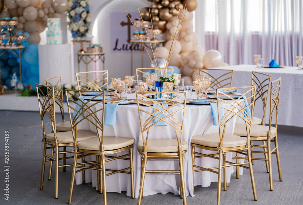 Fototapeta premium Elegante mesa de celebración con sillas doradas y decoración de globos para evento infantil de bautizo