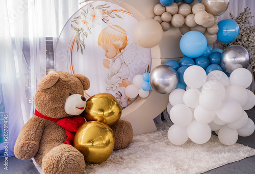 Foto Decoración de bautizo infantil con oso de peluche, globos azules y angelito en e