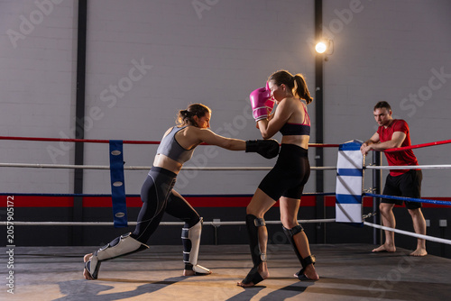 Bilde på lerret Two adult female boxers sparring in ring, throwing jab, wearing sports bras, pin