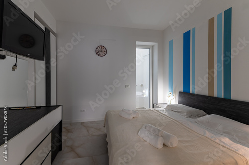 Stylish modern designer bedroom in Italy with elegant contemporary interior design and warm neutral tones. New apartment with refined aesthetic and comfortable atmosphere.