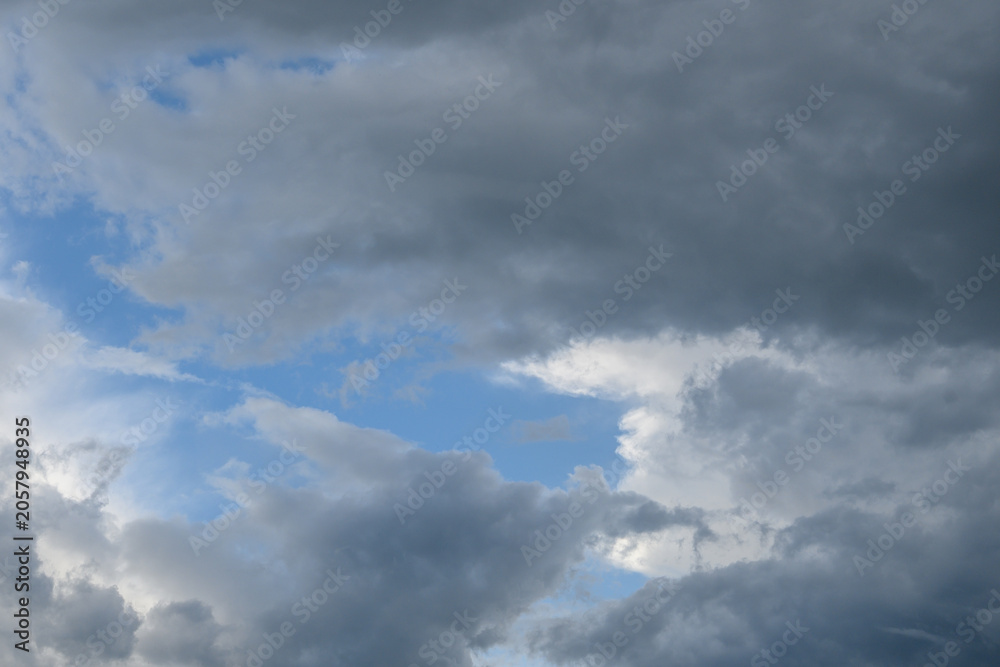 Obraz premium Overcast sky with dense gray clouds and small gaps of blue sky visible between the dark clouds