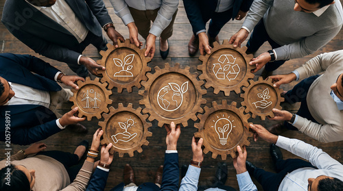 Diverse team of man and woman colleagues holding wooden cogwheels with green ecology symbols. Business collaboration for environmental sustainability and corporate social responsibility project.