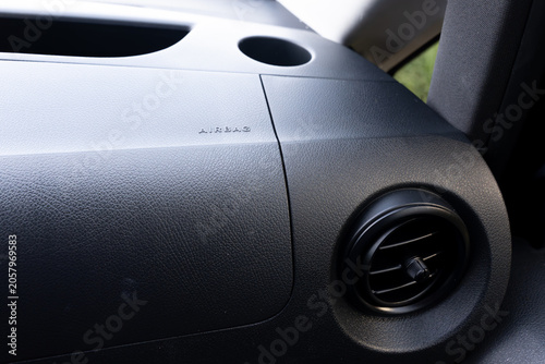 Horizontal photo of a car interior dashboard featuring an airbag panel and ventilation vent, highlighting automotive safety systems, passenger comfort