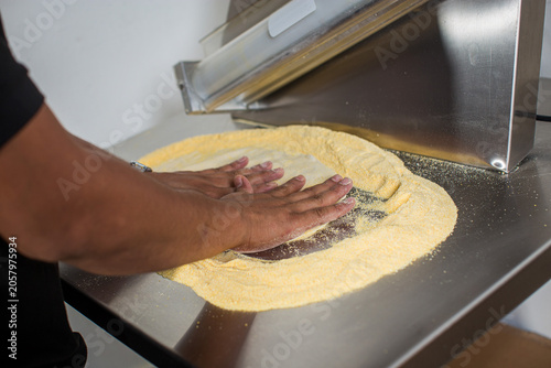 Pizza dough being flattened by hand