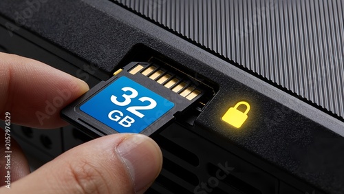 Hand inserting a thirty two gigabyte secure digital memory card into a black electronic device slot featuring a glowing yellow padlock icon indicating data encryption security