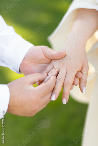 Groom putting wedding ring on bride's finger during ceremony