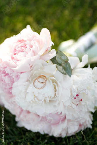 Wedding rings on a bouquet of white and pink peonies