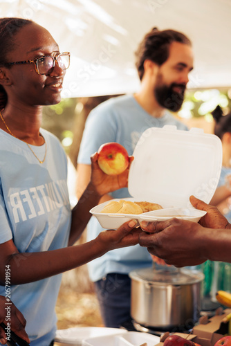 Foto Close-up shot of generous black woman working in community food bank, serving free meals for the needy