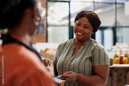 Slika na platnu Female customer buys fresh, healthy groceries and pays with debit card